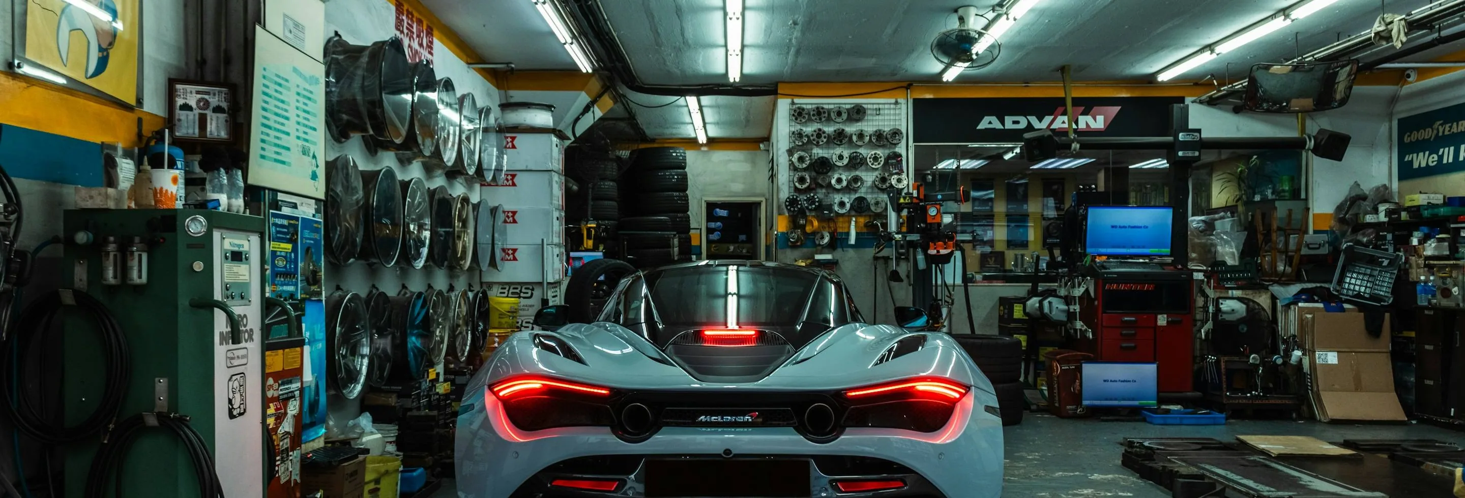 the garage — a British workshop with a car on the ramp, wide