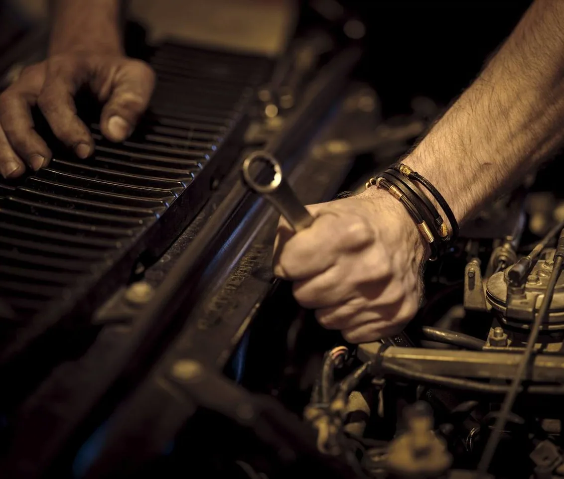 a mechanic's hands working in an engine bay, no face