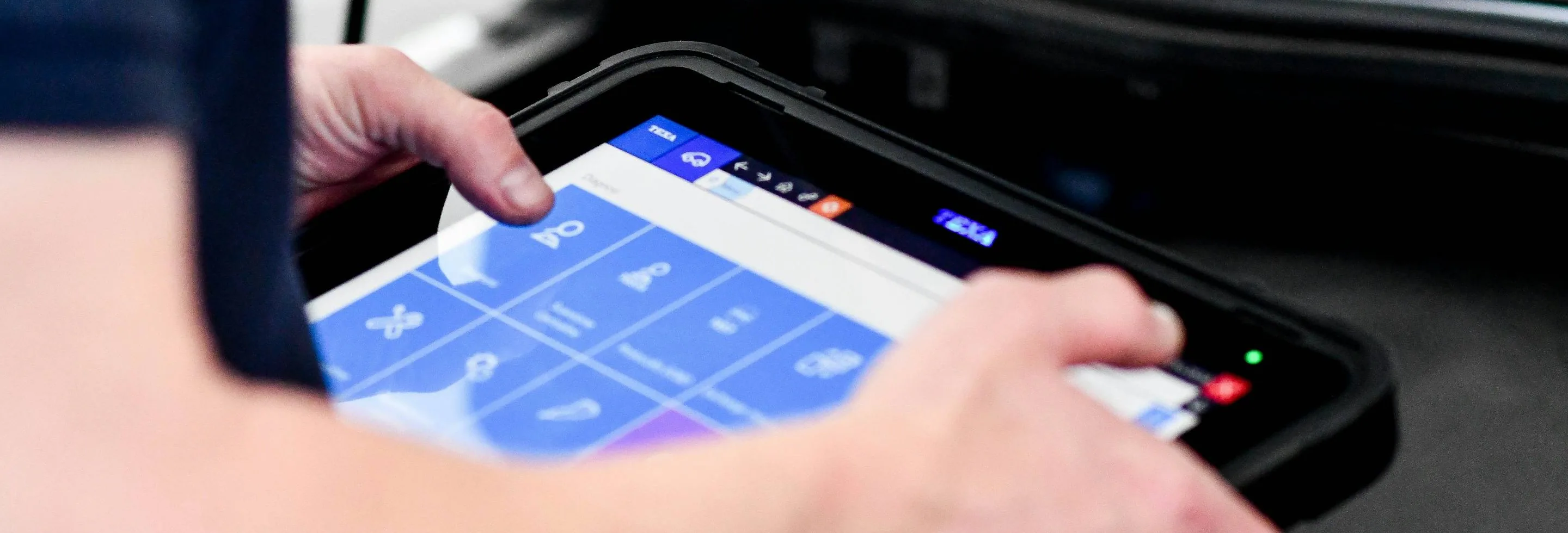 a diagnostic tablet or laptop in use on a car, wide